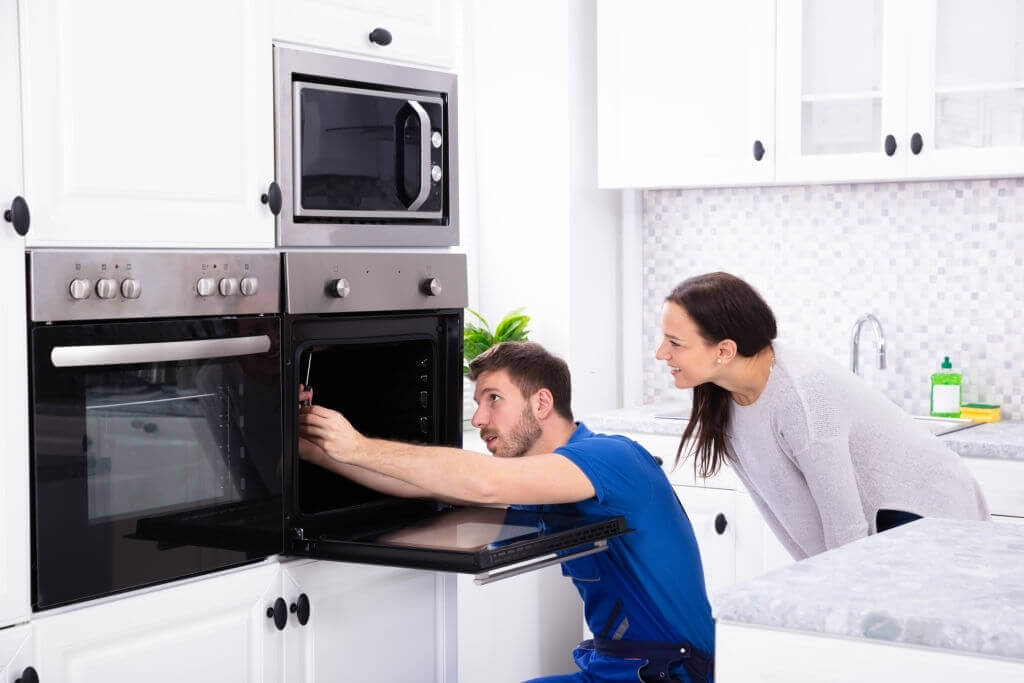 Appliance repair technician fixing the oven